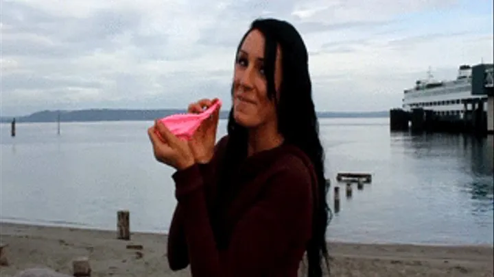 Demi blowing up pink balloon on beach until it pops