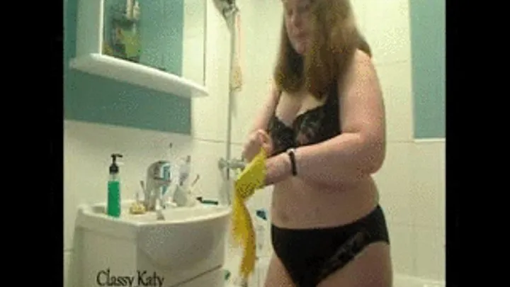 Cleaning the washbasin and mirror in black lacy bra and satiny panties, wearing rubber gloves