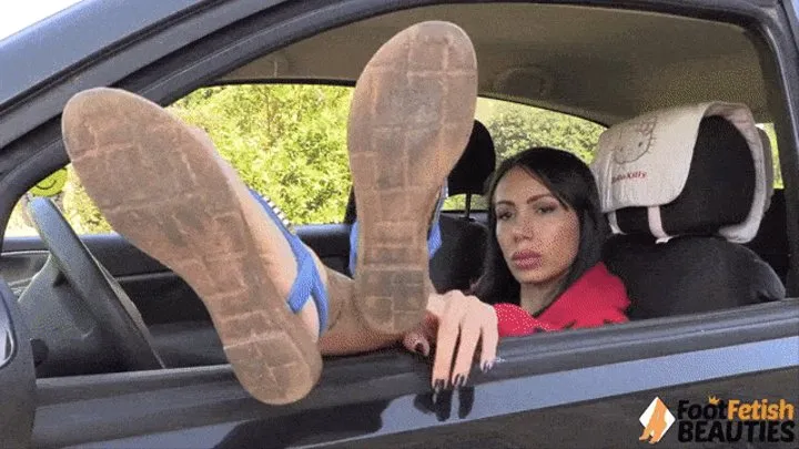 Daniela dangling her sandals while sitting in a car