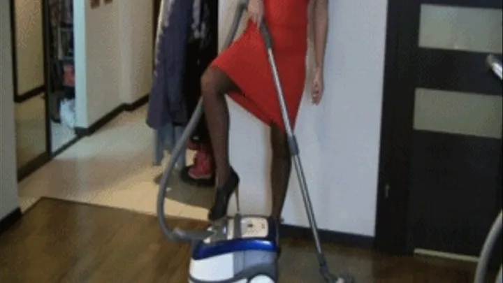 Cleaning by the vacuum cleaner in a red dress.