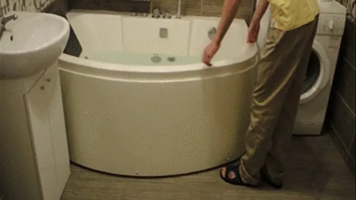 A guy falls in the bathtub with clothes and slippers on - feet exposing