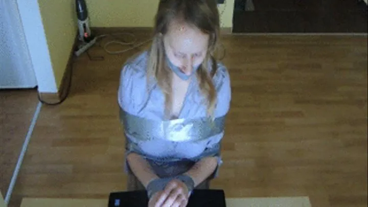 Taped to the chair, sealed mouth, typing on the computer - front view