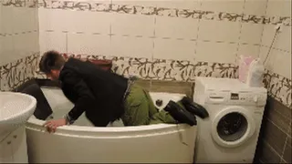 A guy falling in the bathtub fully clothed and showing feet