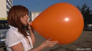 Titi blowing giant orange balloon outdoors ( )