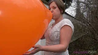 Simona inflates a giant orange balloon outside ( )