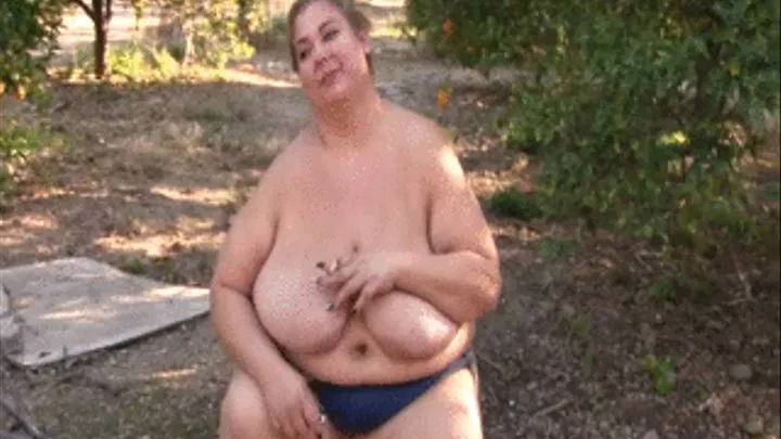 BBW Lola LoveBug is sitting in a orange grove topless smoking a cigarette