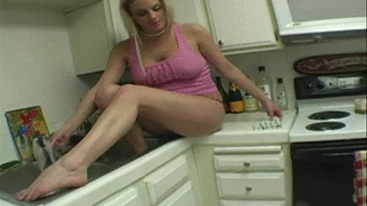 Fantastic blonde cleans her feet in a sink