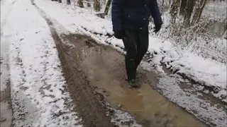 Black rubber boots and winter muddy road