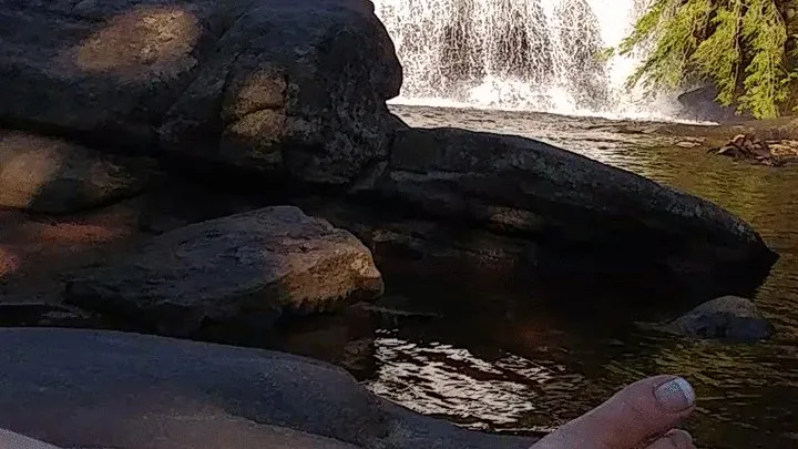 Dangling toes in the water infront of waterfall