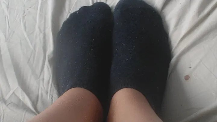 2 old small dirty black sock on feet