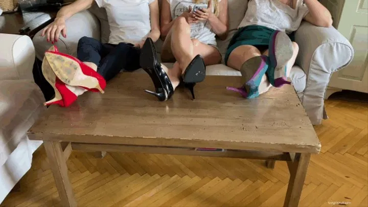THREE GIRLS WATCHING TV IN HIGH HEELS ON THE TABLE