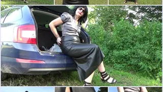 Angela in a satin blouse and a long leather skirt with handcuffs and a wristwatch
