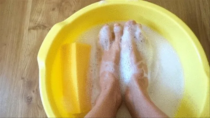 Barefoot playing with my feet with sponge - putting into soap water inside basin with foam