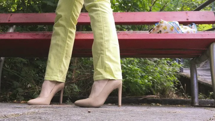 Raven dangling her high heels crossing legs while sitting on a bench outdoor