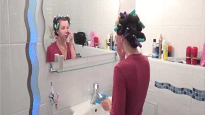 Wearing hair rollers skinny girl puts on face mask