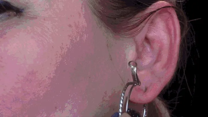 Various earrings and a large needle penetrate the openings of my ear from different angles