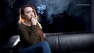 The new girl Julia resting on our black couch and smoking a 100 mm Marlboro Red