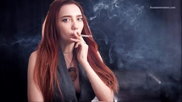 Sexy red-haired girl standing in a smoky room with a 120 mm cigarette in her hand