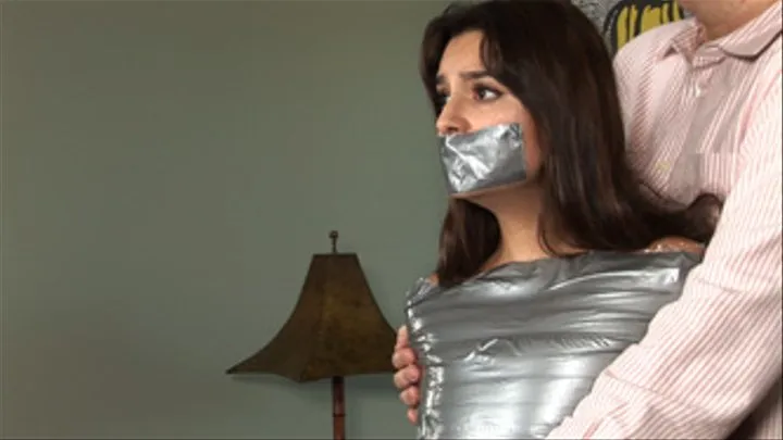 Lovely Carol Luna first stands in ankles-to-shoulders duct-tape mummification, then lies squirming on a couch!