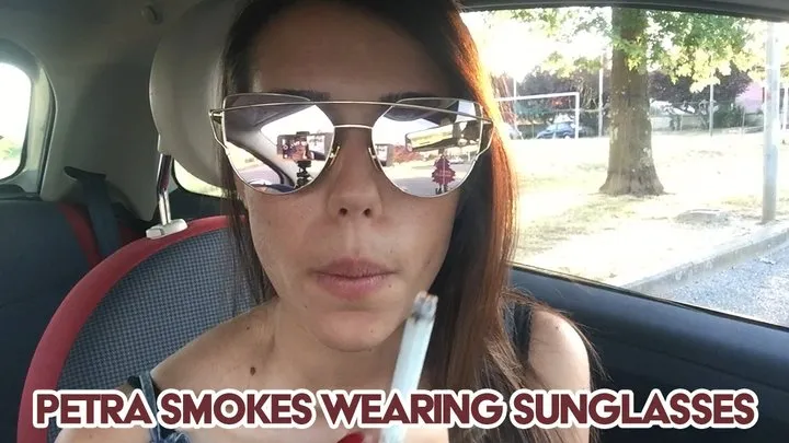 Petra smokes wearing sunglasses