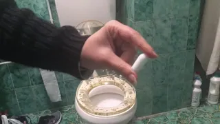 Playing with a white hard suppository on the toilet seat