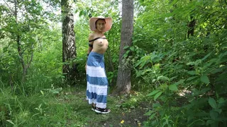 Tied up Sofi walks through the forest in a dress and hat