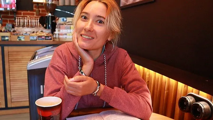 Sofi Reading an erotic novel in a cafe in a handcuffs