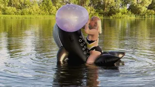 Alla inflates a 16-inch balloon with her mouth, which unexpectedly bursts, and rides on an inflatable whale