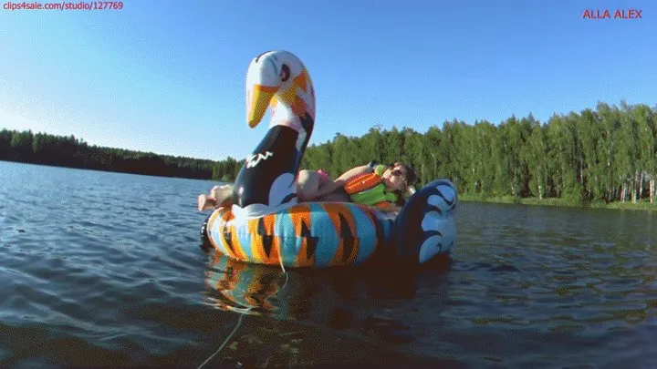 Alla is having a great time swimming on a large bright inflatable swan on the lake!!!