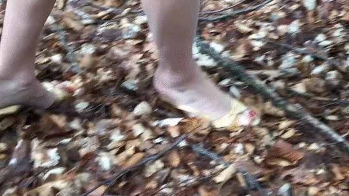 Dasha Kelly is wearing Golden vintage slingback sandals she walks in the wood on a muddy and leafy ground her heels perforate the soft groud