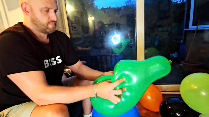 Tom hand pops a pile of under-inflated balloons